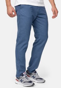 Chinos azul claro con un diseño elegante de pierna recta, que cuentan con bolsillos laterales y una tela suave y transpirable. Combinados con zapatos deportivos grises.