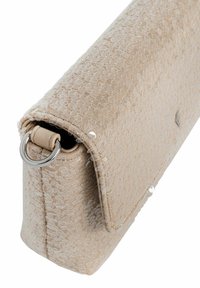 Beżowa torebka z teksturowanej tkaniny o wyraźnym wzorze, z metalowym pierścieniem w kolorze srebrnym i klapką, prezentująca elegancki, minimalistyczny design.