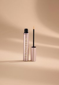 Tubo di eyeliner liquido color rosa oro con pennellino applicatore nero. Il tappo è cilindrico, decorato con scritte in rilievo. Finitura opaca liscia.