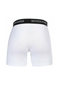 Weiße Baumwoll-Boxershorts mit einem schwarzen elastischen Bund, der den Text "SCOTCH & SODA" trägt. Glatte Textur, enganliegendes Design, standardmäßige Beinlänge.