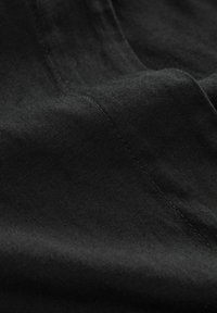 Tela negra con una textura suave y detalles de costura finos. El material parece ligero y suave, con sutiles reflejos de luz.
