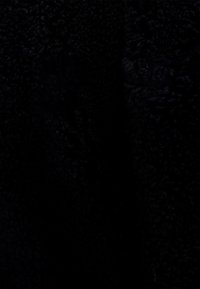 Textil negro con una superficie suave y texturizada, que presenta un acabado blando e irregular típico de los materiales de forro polar. Sin patrones o acentos visibles.