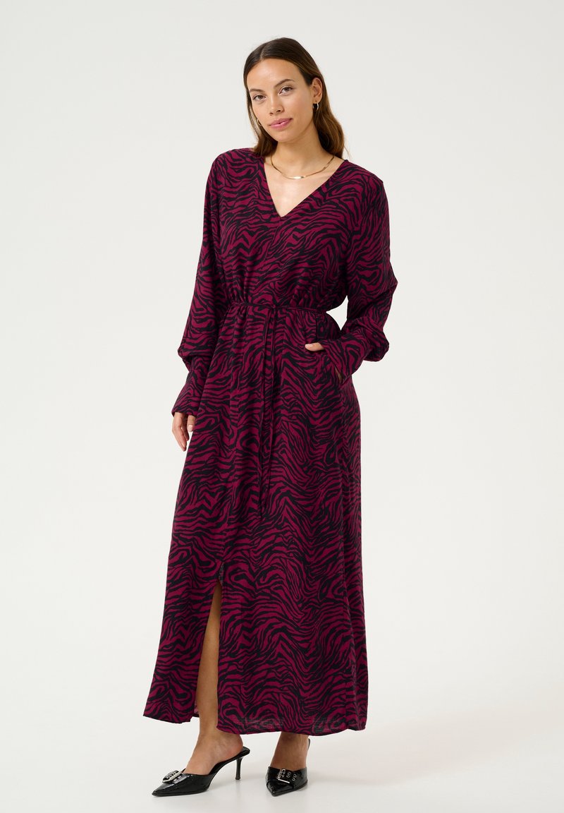 Maxi dress in fuchsia with black zebra stripes, featuring long sleeves, a V-neck, belt at the waist, and side pockets.