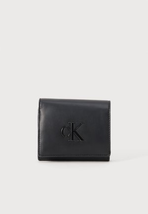 Cartera de cuero negra con el logo "cK" en relieve centrado en la parte delantera, forma rectangular, costuras limpias a lo largo de los bordes sobre un fondo claro y sencillo.