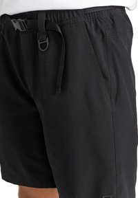 Pantalones cortos negros hechos de un tejido ligero con una superficie texturizada. Cuentan con una cintura ajustable y bolsillos laterales.