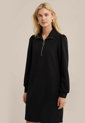 Black, long-sleeve dress with a zippered collar. Features a relaxed fit and slightly puffed shoulders. Made from smooth fabric.