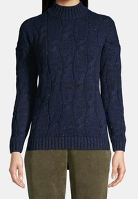 Pull en maille bleu marine avec un col montant, un motif torsadé et un ourlet côtelé. Texture douce avec des nuances subtiles de couleur partout.