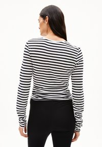 Zwart-wit gestreepte langemouwen shirt met een ronde hals, aansluitende silhouet en zachte textuur, gecombineerd met zwarte leggings.