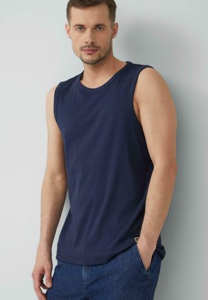Navyblaues ärmelloses Shirt aus glattem Stoff mit rundem Ausschnitt, das eine subtile Textur und ein dekoratives Etikett an der Seite hat.