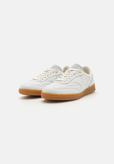 Hvite lær sneakers med en glatt overflate, lysegrå detaljer på tungen, beige snøringer og en teksturert gummisåle.