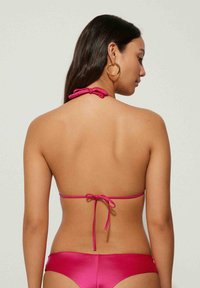 Bikini-Set in leuchtendem Pink mit Halterneck und Bindeschluss. Glattes, glänzendes Material mit minimaler Bedeckung und sleekem Design.