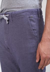 Pánské námořnické kalhoty s texturovaným vzorem, stahovací pas a boční kapsy. Obsahují malý kovový akcent na pase.