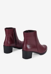 Botas de tobillo de cuero burdeos con un acabado liso, punta redondeada, tacón cuadrado de 3 pulgadas y cierre de cremallera lateral.