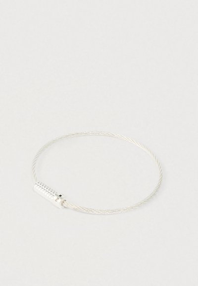 Strieborný skrútený drôtový náramok s textúrovaným cylindrickým zapínaním na jednoduchom bielom pozadí.