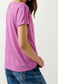 Rosa kortärmad T-shirt i ett mjukt tyg, med en avslappnad passform och rundad halsringning. Tillsammans med blå jeans, vilket visar en avslappnad stil.