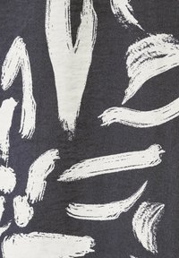 Zwarte stof met grote witte penseelstreken, met variërende breedtes en texturen, die een dynamisch, abstract ontwerp creëren.