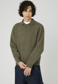 Pull en olive avec col zippé, poignets et ourlet côtelés. Fabriqué dans un tissu doux et texturé.