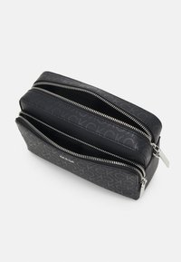 Black dual-zip cosmetic bag with logo pattern, smooth texture, silver-tone hardware, and a compact rectangular shape.