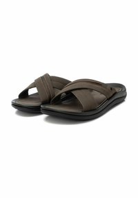 Sandalias de deslizar marrones con tiras cruzadas hechas de material suave y suelas de goma negra. Presentan detalles de costuras naranjas.