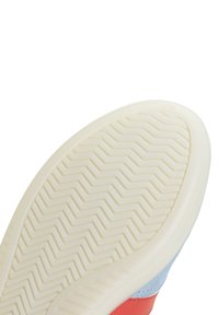 Potplat u svijetlijem bež gumi s teksturiranim cik-cak uzorkom. Gornji dio je od plave antilop kože s crvenim detaljima.