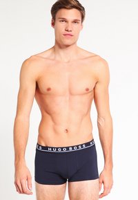 Marineblaue Boxershorts mit einem weißen HUGO BOSS Logo am Bund, aus Baumwolle mit glattem Material, figurbetontes Design.