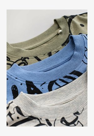 Trīs salocītas džemperi ar apaļu kaklu krāsās bēšā, zilā un olīvzaļā ar melniem grafiskiem tekstu dizainiem uz vienkārša fona.