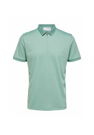 Menta zöld pólóing sima anyagból, cipzáras gallérral, rövid ujjakkal és kontrasztos textúrával ellátott díszítéssel az ujjak mentén.