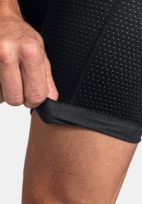 Schwarze Sportshorts aus einem strukturierten, atmungsaktiven Stoff. Nennenswerte Merkmale sind das körpernahe Design und gitterartige Perforationen für Belüftung.
