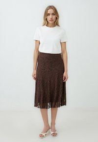 Brauner midilanger Spitzenrock mit floralen Mustern, aus halbtransparentem Stoff, kombiniert mit einem schlichten weißen T-Shirt. Einfaches Design mit ausgestellter Form.