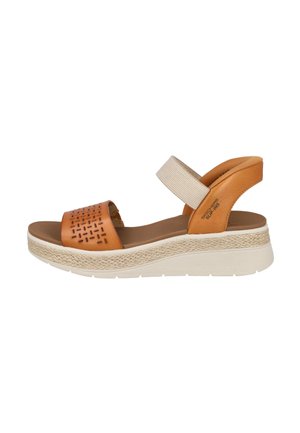 Sandalia de plataforma marrón con suela tejida, tiras perforadas delanteras y correa elástica beige para el tobillo, vista lateral sobre fondo blanco.