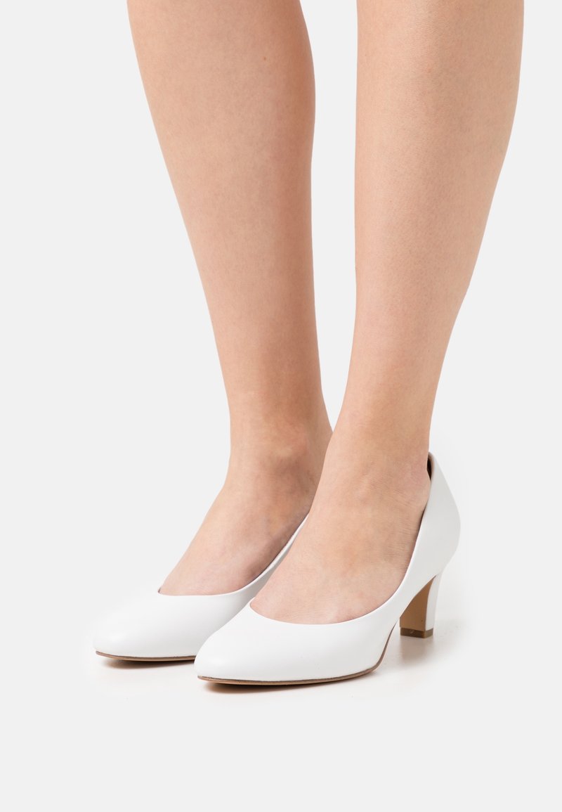 Chaussures à talons hauts en cuir blanc avec un bout arrondi et un talon court et effilé. Texture lisse et design minimaliste.
