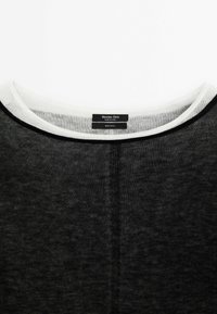 Pull fin en laine noire avec encolure ronde blanche et couture verticale centrée, étiqueté Massimo Dutti, fabriqué en Chine.