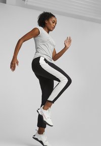 T-shirt gri cu un design simplu la contur, asortat cu pantaloni negri cu dungi albe pe laterale. Pantofi sport cu detalii din plasă.