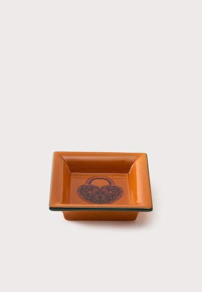Plat carré en céramique orange avec un motif décoratif de cadenas foncé en forme de cœur au centre.