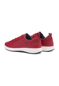 Red leather sneakers with a smooth texture, white rubber sole, and round laces. Features a low profile and heel pull tab for easy wear.