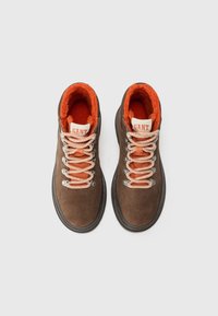 Botas de senderismo de ante marrón con forro de lana naranja, ojales plateados y cordones decorados. Marca GANT en la lengüeta.
