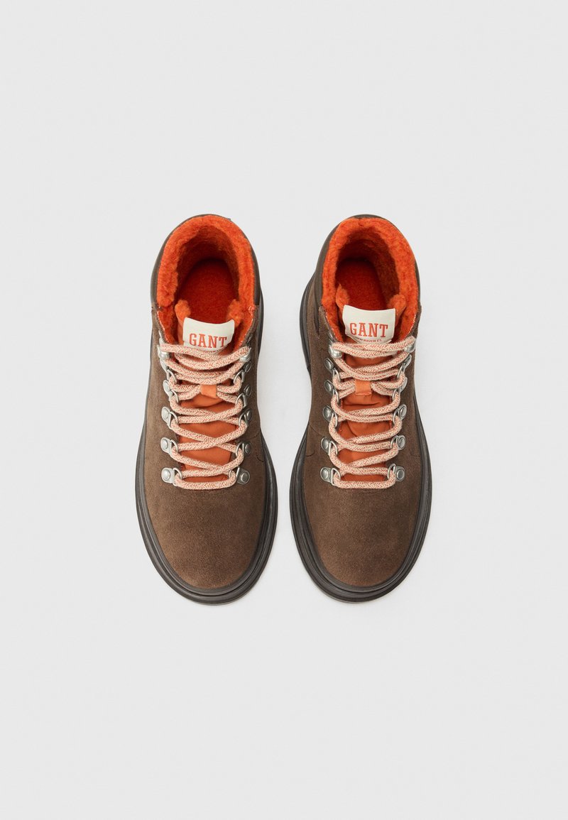 Braune Wildleder-Wanderschuhe mit orangefarbenem Fleece-Futter, silbernen Ösen und gemusterten Schnürsenkeln. GANT-Logo auf der Zunge.