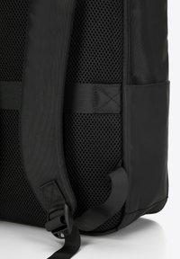 Zaino nero con pannello in rete testurizzata, tessuto liscio, tracolla regolabile e chiusura a fibbia. Costruzione robusta con un design elegante.