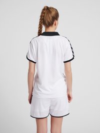 Hvid atletisk skjorte med korte ærmer og sorte detaljer, parret med hvide shorts med sorte kanter. Designet til komfort og bevægelighed.