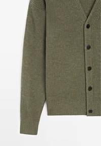 Cardigan a maniche lunghe di colore verde oliva con costine, scollo a V e cinque bottoni neri sul lato destro, su uno sfondo bianco.