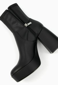 Černé vysoké kozačky na kotníky z hladké kůže, s bočním zipem, masivním čtvercovým podpatkem a kulatou špičkou. Texturované detaily na boku.