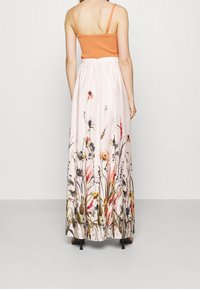 Maxikjol med blommönster i rosa, med gröna, orange och lila detaljer; tillverkad av mjukt, lätt tyg.