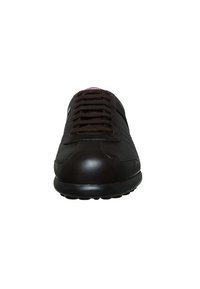 Zapatilla de deporte de color marrón oscuro con acabado de cuero suave, diseño con cordones y suela de goma. Presenta detalles de costura y una punta redonda.
