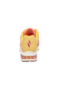 Baskets sportives avec un design rose et jaune, tige en mesh, accents texturés, et une semelle amortissante transparente avec un logo à l'arrière.