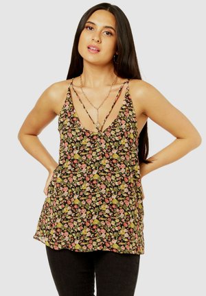 Floral tank top featuring a black background with small pink and green flowers, deep V-neck, and thin, crisscross straps.