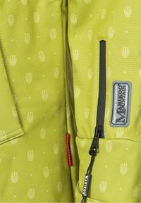 Zielona kurtka z fakturą, z delikatnym wzorem muszelek, czarną kieszenią na zamek oraz metką z napisem "MARIKOO" w kolorze srebrnym.