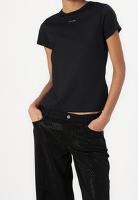 Sort T-shirt lavet af blødt stof med korte ærmer og rund halsudskæring, med et lille hvidt Calvin Klein logo på brystet.
