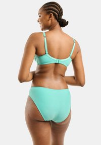 Un bikini verde menta composto da un reggiseno ben sagomato con spalline regolabili e uno slip a vita alta abbinato. Tessuto liscio e design minimalista.
