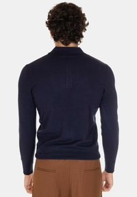 Maglione a maniche lunghe di colore blu navy, con colletto rotondo, forma attillata e polsini a costine, caratterizzato da un dettaglio di cucitura sul retro. Texture morbida con finitura semplice.