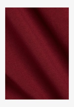 Mørkerødt stof med en glat tekstur, der har et ribbet mønster og let stretch. Lyset reflekteres subtilt på overfladen.